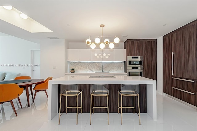 kitchen featuring backsplash, double oven, pendant lighting, light tile patterned floors, and white cabinetry