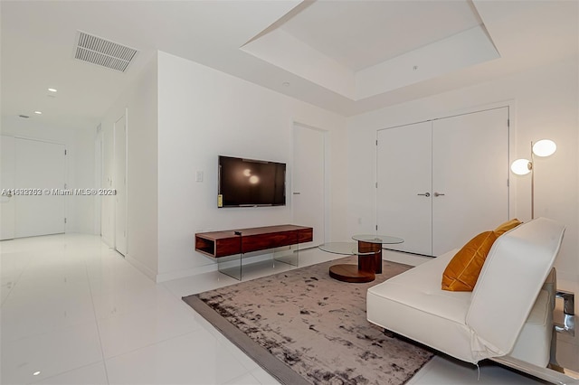 living room with light tile patterned floors and a tray ceiling