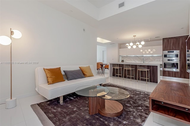 living room featuring sink, light tile patterned flooring, and a chandelier