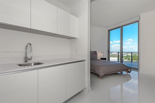 tiled bedroom featuring access to exterior, a wall of windows, and sink