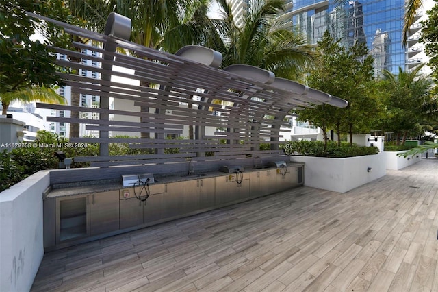 wooden deck with a pergola, exterior kitchen, and sink