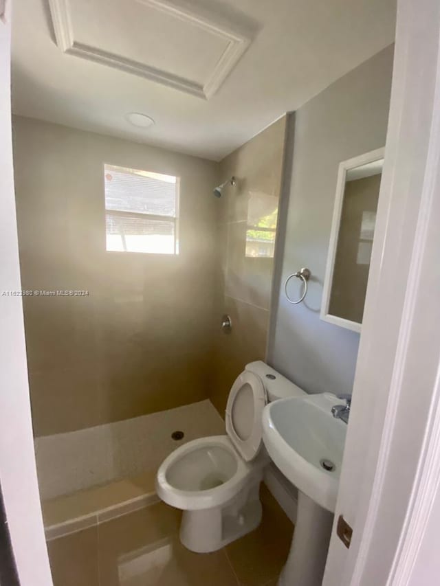 bathroom featuring tiled shower, tile patterned floors, sink, and toilet