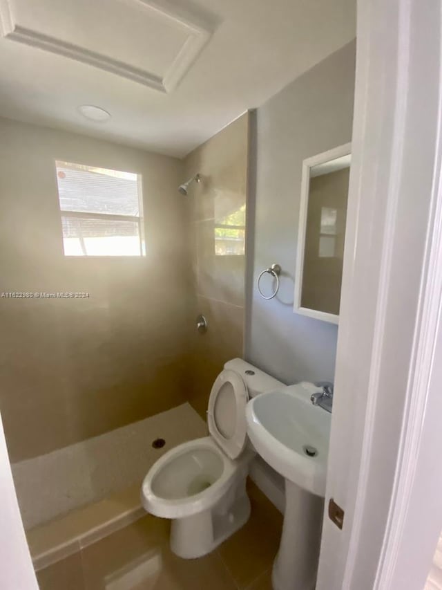 bathroom featuring toilet, a tile shower, and tile patterned flooring