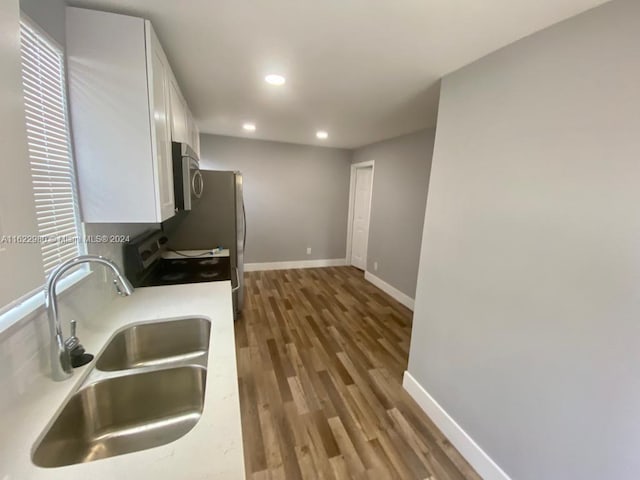 kitchen with sink, white cabinetry, range, and hardwood / wood-style flooring