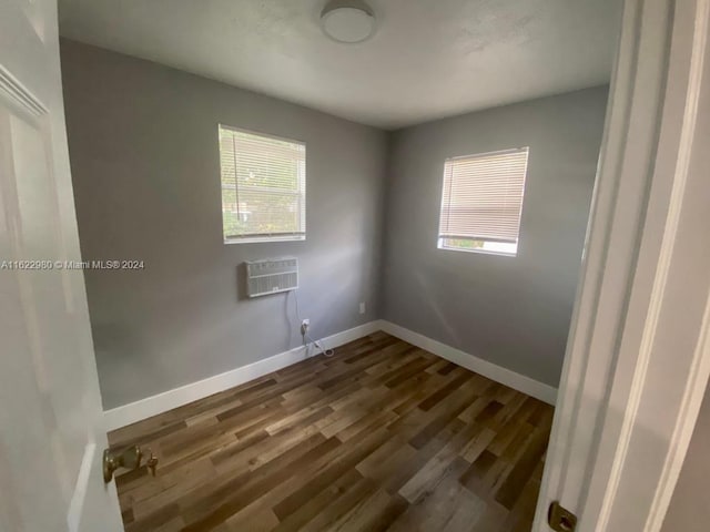 empty room featuring a wall mounted AC and hardwood / wood-style floors