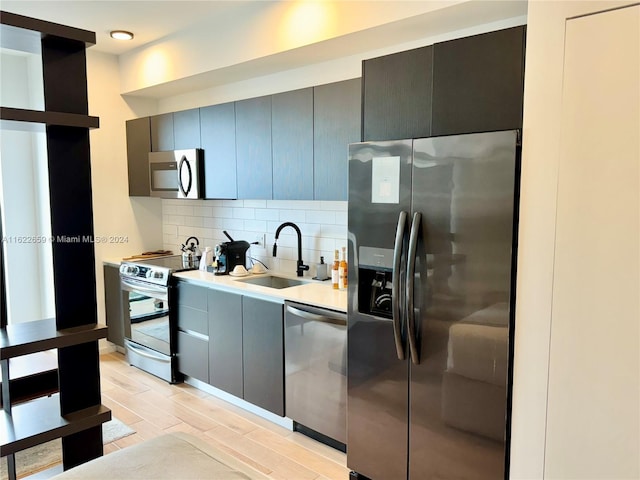 kitchen with sink, stainless steel appliances, gray cabinetry, and tasteful backsplash