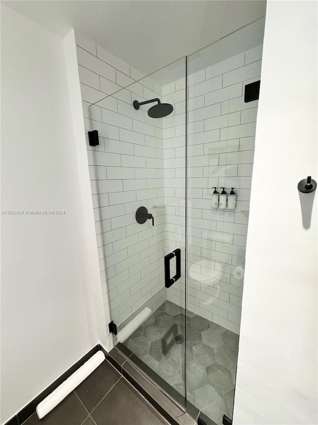 bathroom with tiled shower and tile patterned floors