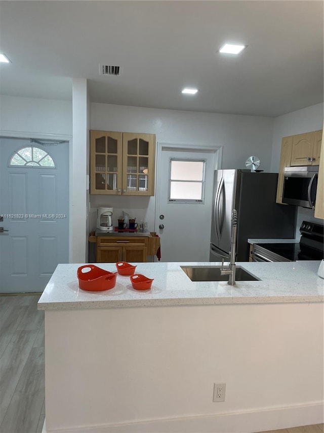 kitchen with sink, appliances with stainless steel finishes, light wood-type flooring, and light stone counters