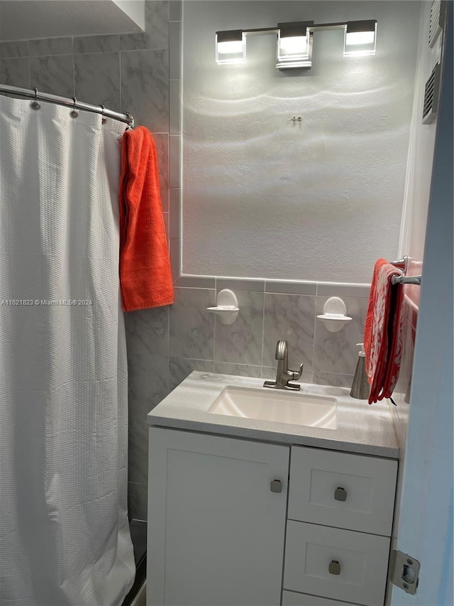 bathroom featuring vanity, tile walls, and tasteful backsplash