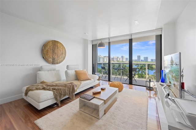 living room featuring expansive windows, baseboards, and wood finished floors