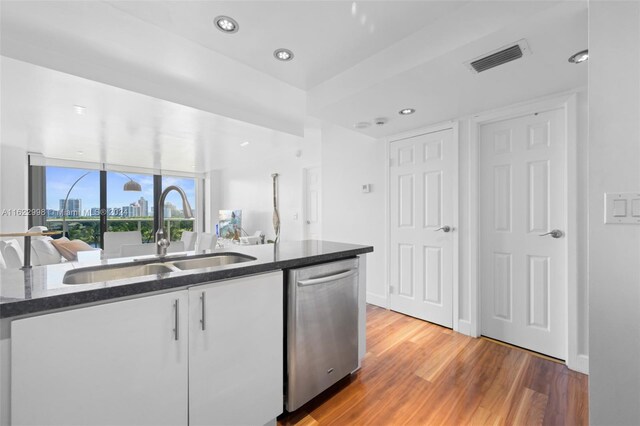 kitchen with dark stone countertops, sink, dishwasher, and wood-type flooring