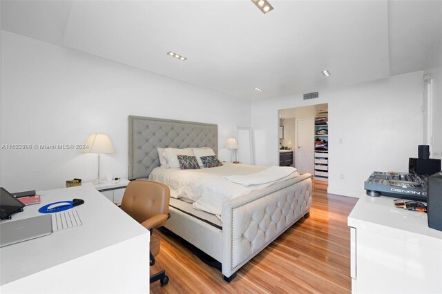 bedroom with connected bathroom and light wood-type flooring