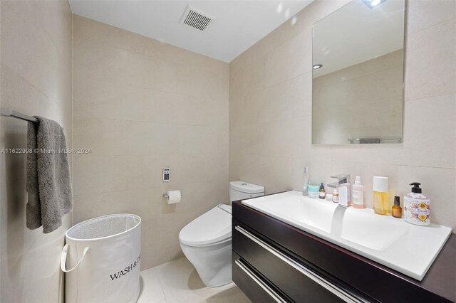 bathroom with vanity, toilet, tile walls, and tile patterned flooring