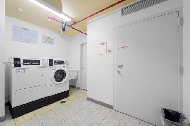 laundry room with washer and clothes dryer and light tile patterned floors