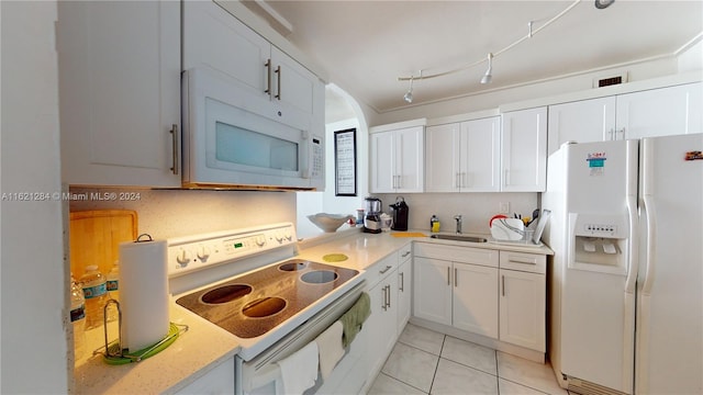 kitchen with track lighting, white appliances, light tile patterned floors, and white cabinets