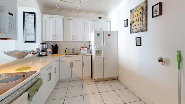 kitchen with white appliances, white cabinets, sink, light tile patterned floors, and crown molding