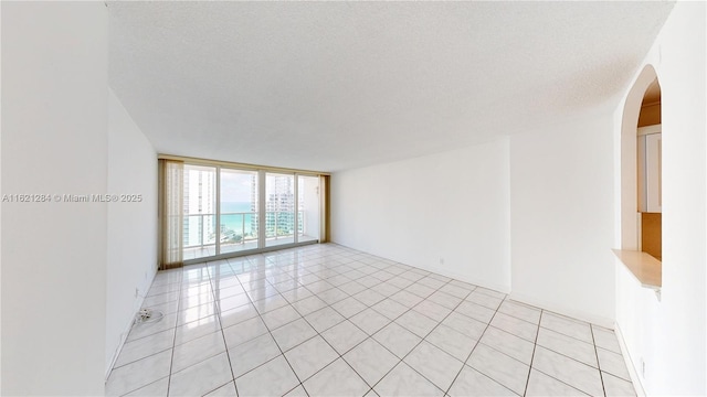 dining space featuring a wall of windows, a textured ceiling, and light tile patterned floors