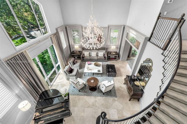 living room with a high ceiling, a notable chandelier, and a healthy amount of sunlight