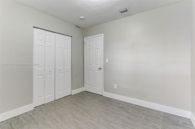 unfurnished bedroom with light wood-type flooring and a closet