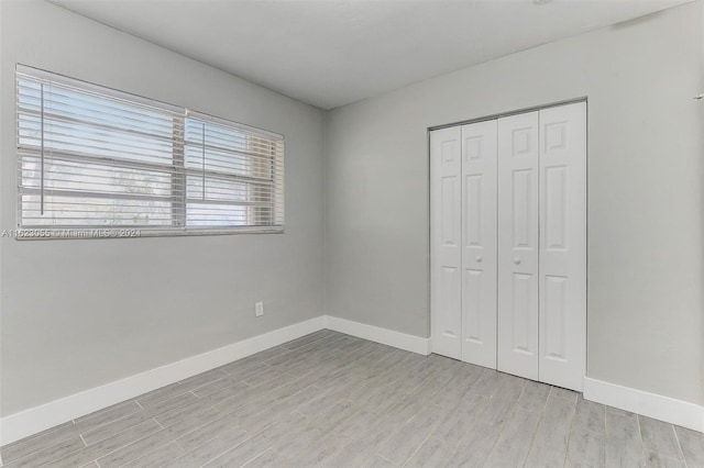 unfurnished bedroom with a closet, light hardwood / wood-style floors, and multiple windows