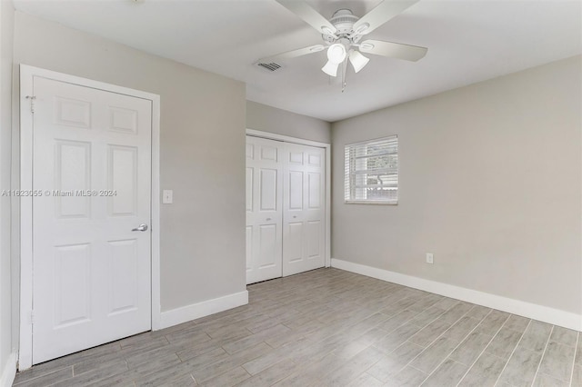 unfurnished bedroom with light wood-type flooring, ceiling fan, and a closet