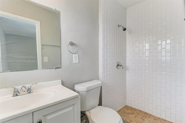 bathroom with a tile shower, vanity, and toilet