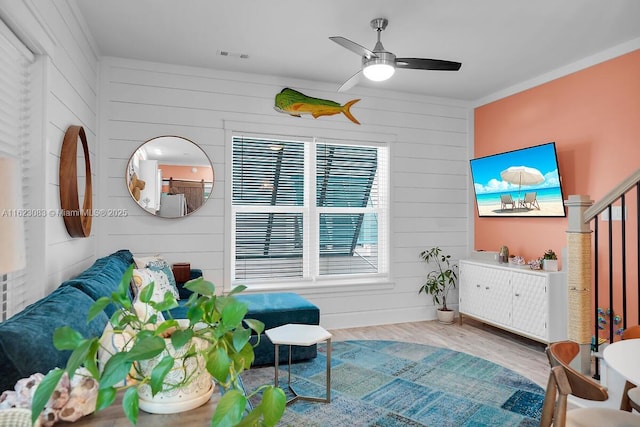 interior space with wood-type flooring, wood walls, ceiling fan, and ornamental molding