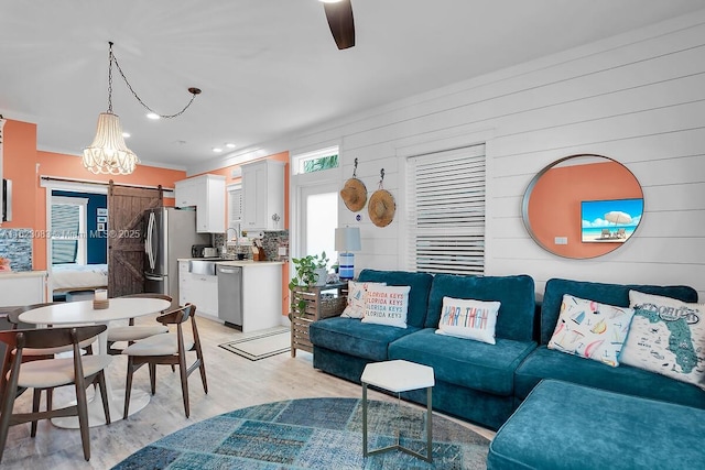 living room featuring wooden walls, light hardwood / wood-style flooring, ceiling fan, and a barn door