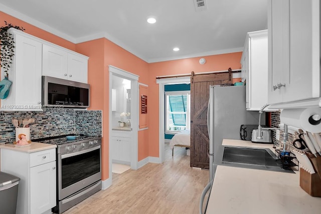 kitchen featuring a barn door, white cabinetry, and appliances with stainless steel finishes