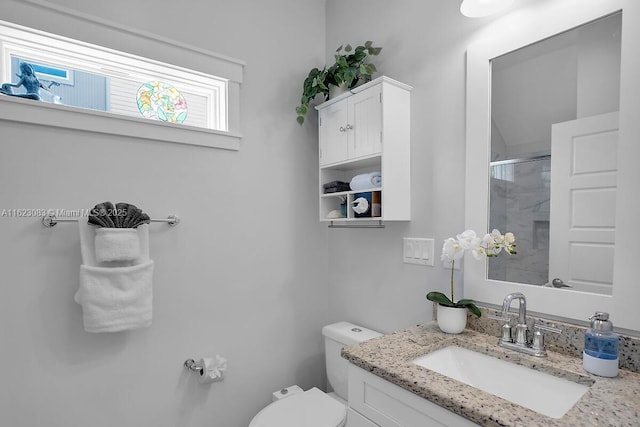 bathroom featuring toilet, a shower with shower door, and vanity