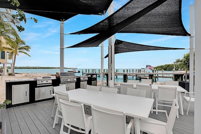 deck with area for grilling, an outdoor kitchen, and a water view