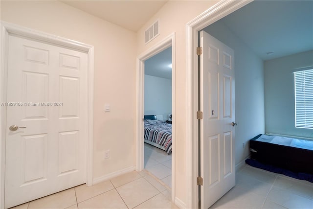 hallway featuring light tile patterned floors, visible vents, and baseboards