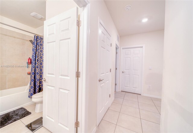 hallway with light tile patterned flooring and baseboards