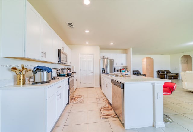 kitchen featuring visible vents, arched walkways, appliances with stainless steel finishes, white cabinets, and light tile patterned floors