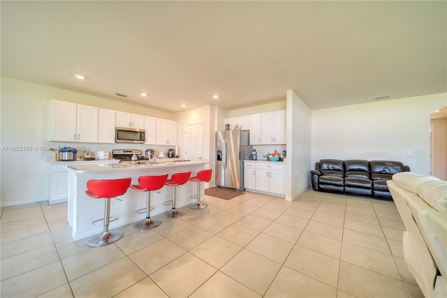 kitchen featuring light tile patterned flooring, stainless steel appliances, light countertops, white cabinetry, and open floor plan