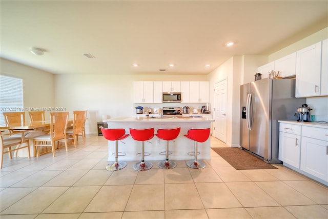 kitchen with a breakfast bar, light countertops, white cabinets, and stainless steel appliances