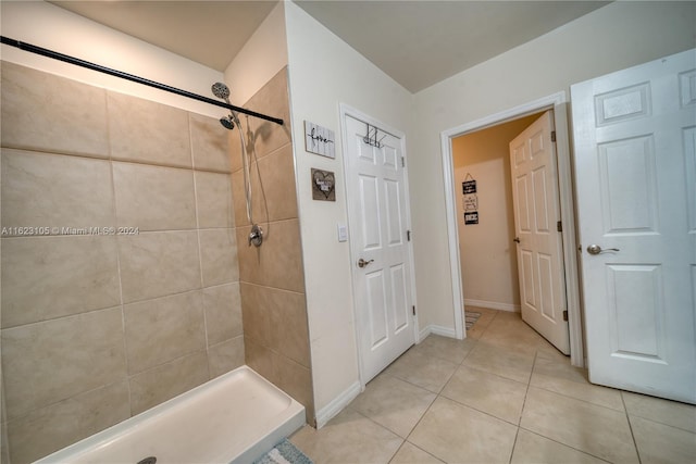 full bathroom featuring baseboards, tile patterned flooring, and a tile shower