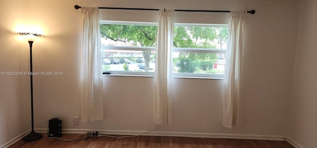 spare room with a wealth of natural light and hardwood / wood-style floors