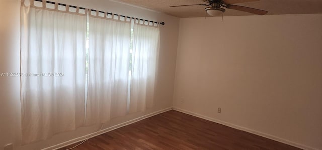 unfurnished room with ceiling fan and dark wood-type flooring