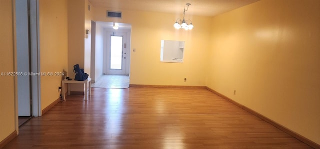 spare room featuring a chandelier and hardwood / wood-style flooring