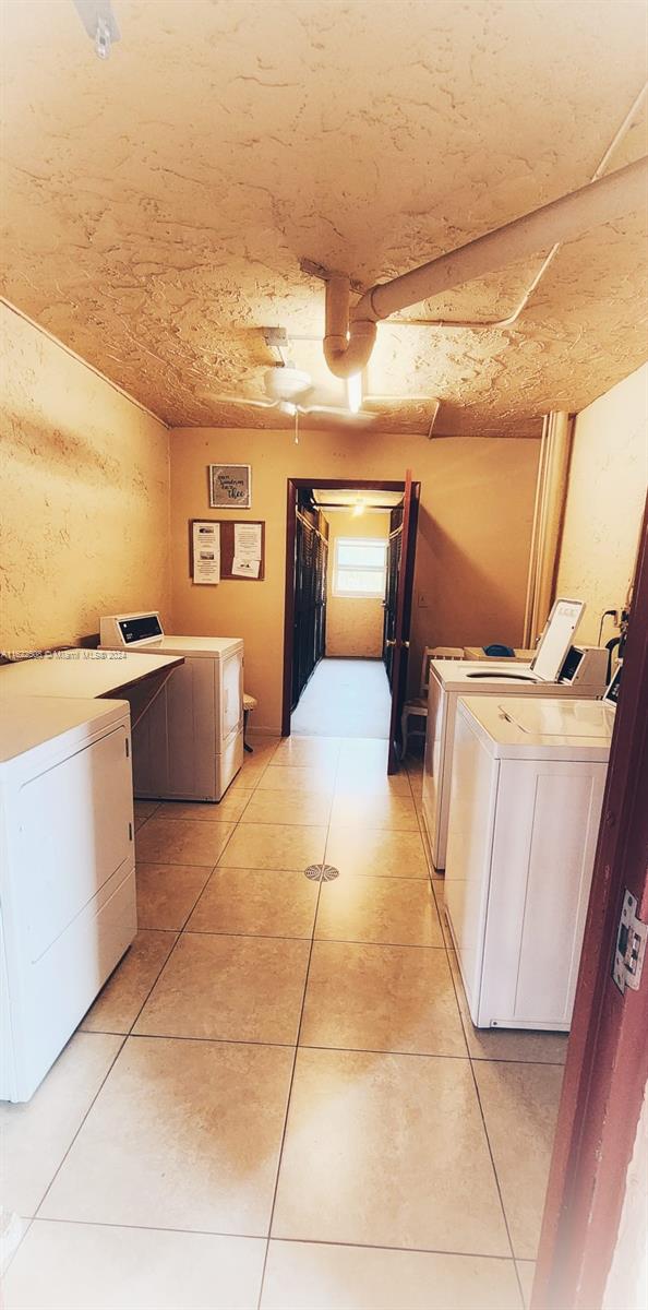 clothes washing area with washing machine and dryer and light tile patterned floors