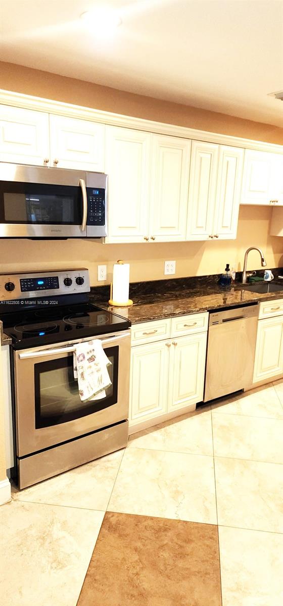 kitchen with stainless steel appliances, sink, and light tile patterned floors