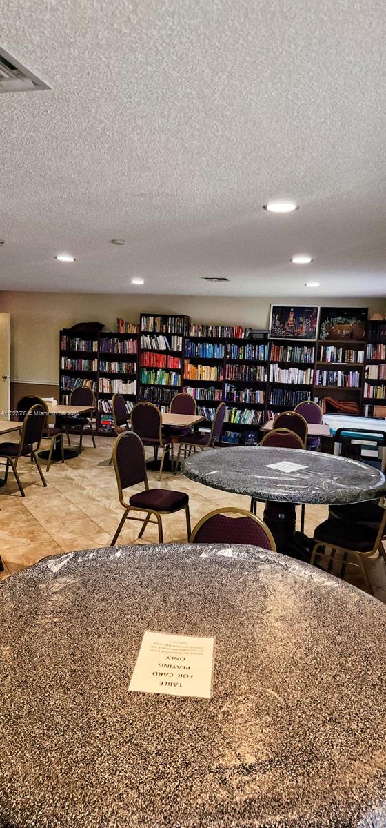 game room with a textured ceiling and light tile patterned floors