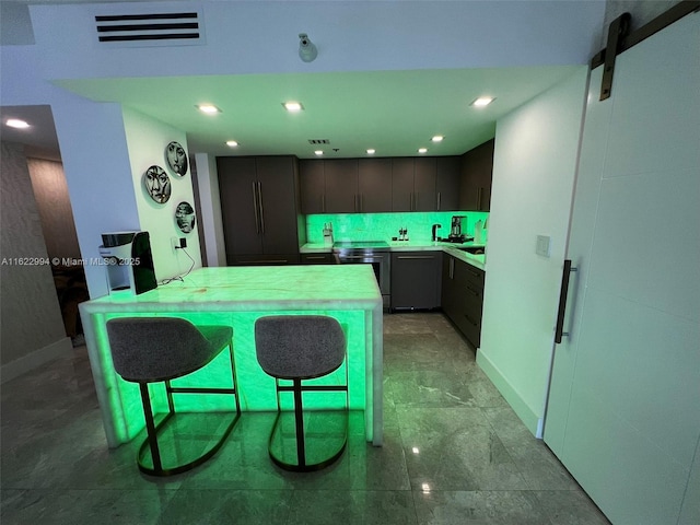 kitchen with a barn door, kitchen peninsula, a kitchen bar, decorative backsplash, and dishwashing machine