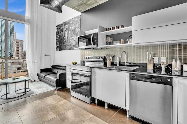 bar with white cabinets, light tile patterned flooring, sink, backsplash, and appliances with stainless steel finishes