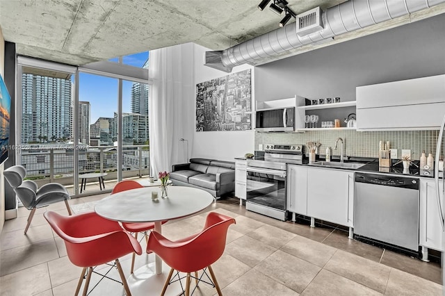 kitchen featuring light tile patterned flooring, sink, tasteful backsplash, white cabinetry, and appliances with stainless steel finishes