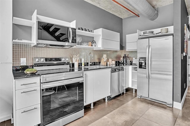 kitchen with light tile patterned flooring, sink, white cabinetry, backsplash, and appliances with stainless steel finishes