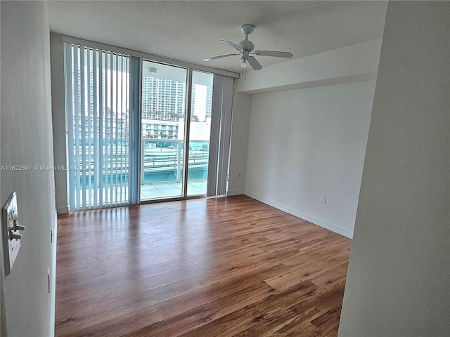 spare room with floor to ceiling windows, hardwood / wood-style flooring, and ceiling fan