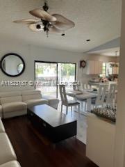 living room with dark wood-type flooring and ceiling fan