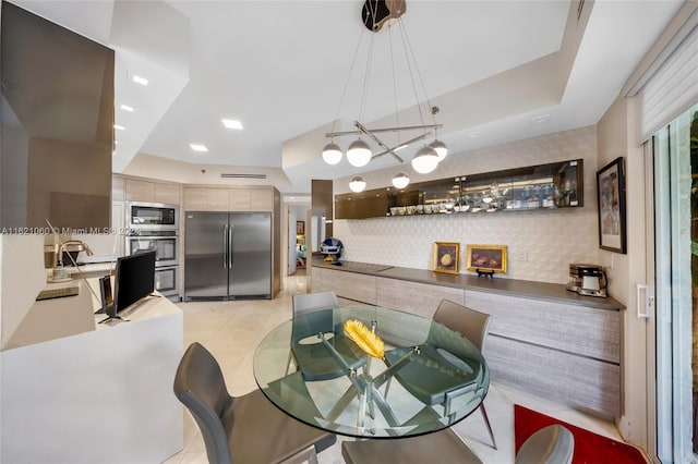 dining area featuring a raised ceiling, light tile patterned floors, and sink